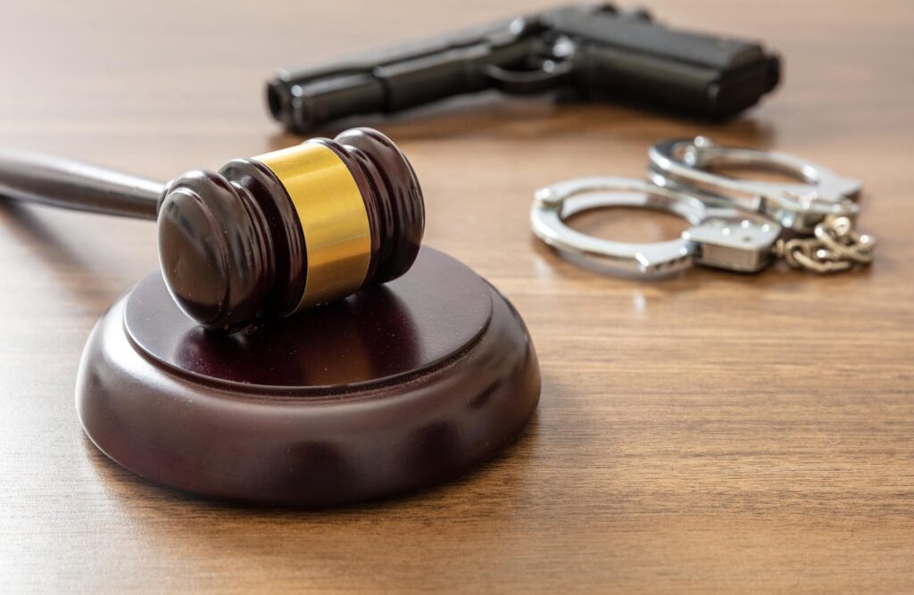 Sanz Bremond Abogados, abogados especialistas en derecho civil y sucesiones en Castellón de la Plana. Mallete junto a un arma y unas esposas.