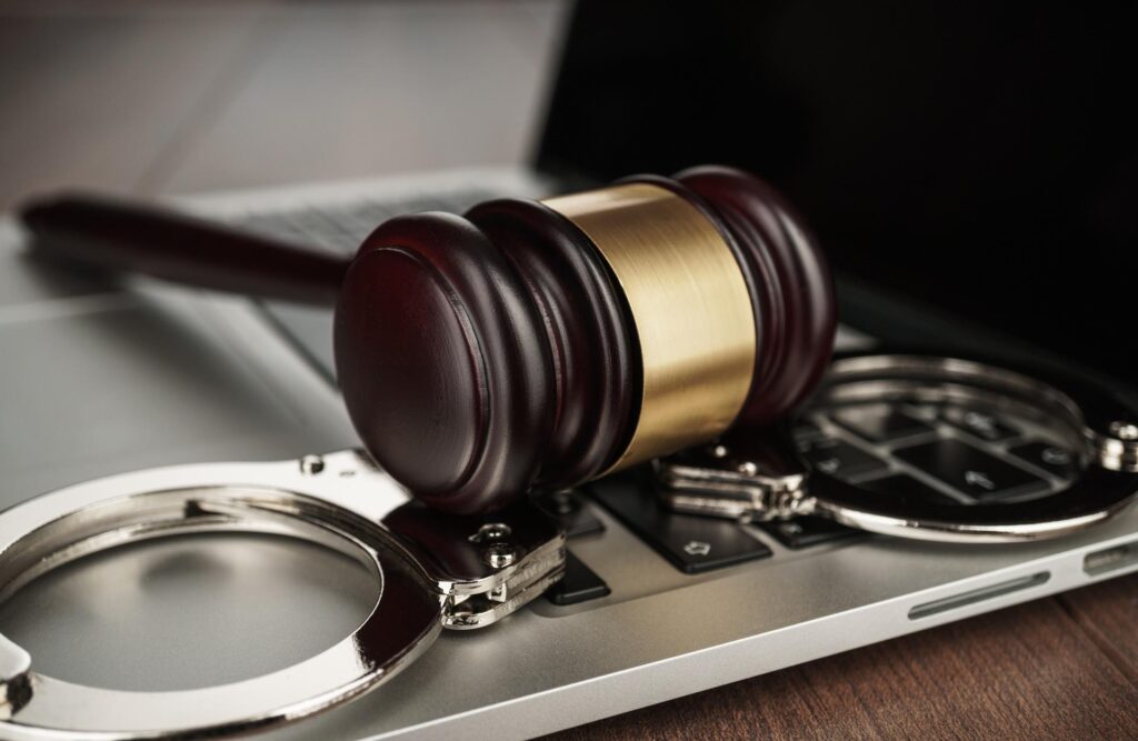 Sanz Bremond Abogados, asesoría legal integral en derecho penal y administrativo en Castellón de la Plana. Mallete sobre unas esposas y un portátil.