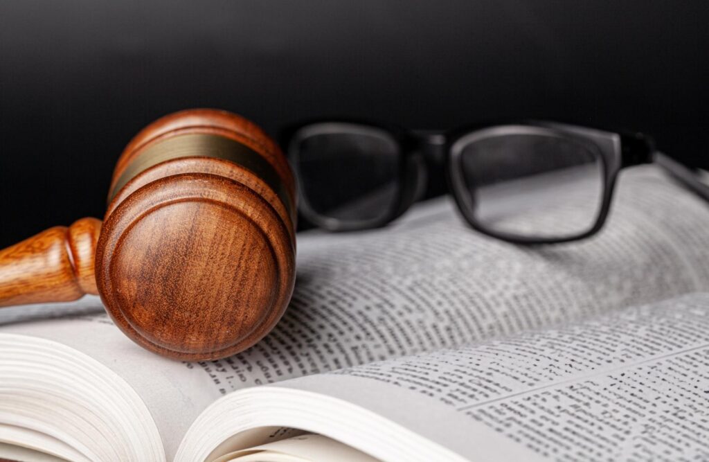 Sanz Bremond Abogados, asesoría legal integral en derecho penal y administrativo en Vila-real. Mallete y unas gafas sobre un libro.